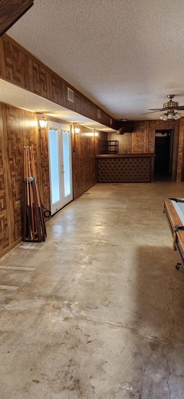 unfurnished living room with wood walls, concrete flooring, and a textured ceiling