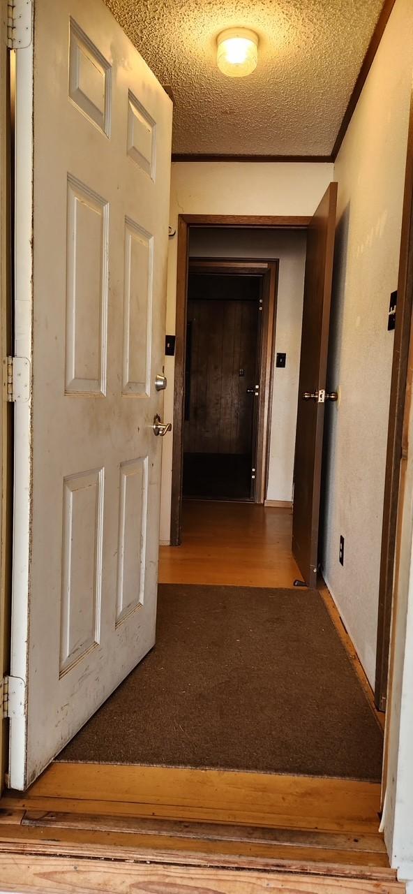 hall featuring ornamental molding, a textured ceiling, and wood finished floors