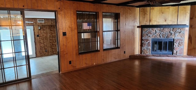 unfurnished living room with a fireplace, a ceiling fan, wooden walls, wood finished floors, and baseboards