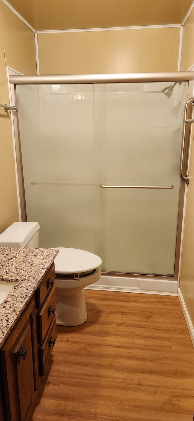 full bathroom with toilet, wood finished floors, vanity, and a shower stall