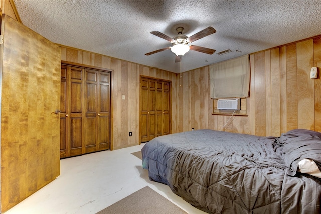 2180 Washington Ave, Alvin, TX 77511 - bedroom with finished concrete flooring, a textured ceiling, visible vents, wooden walls, and two closets