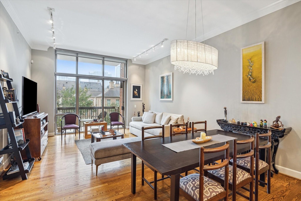 dining area with light hardwood / wood-style floors, rail lighting, a wall of windows, and a notable chandelier