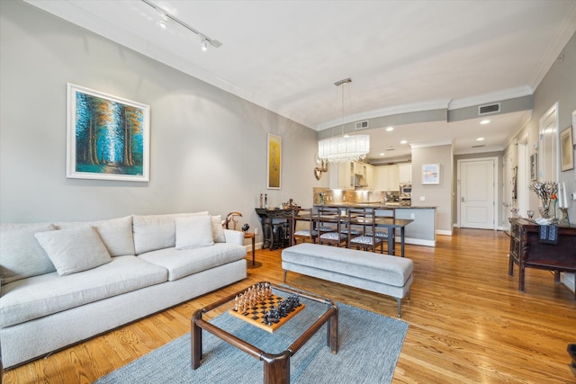 living room with track lighting, ornamental molding, and light hardwood / wood-style floors