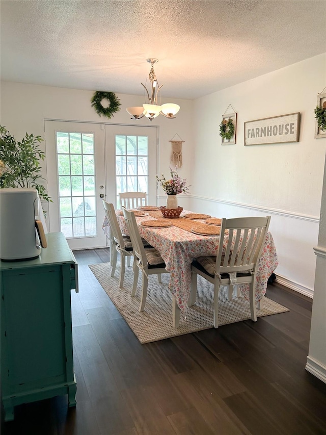 dining area with french doors, dark wood-type flooring, a chandelier, and a textured ceiling