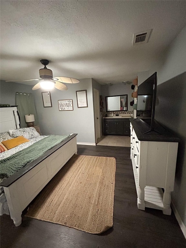 bedroom with a textured ceiling, ceiling fan, and dark hardwood / wood-style floors