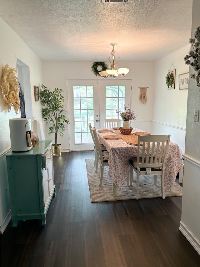 dining space with dark hardwood / wood-style floors, a chandelier, and a textured ceiling