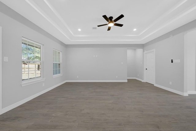 empty room featuring ceiling fan, wood-type flooring, and a tray ceiling