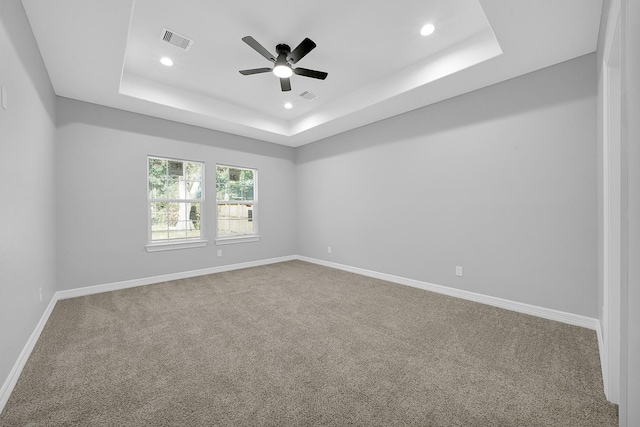 unfurnished room with ceiling fan, carpet flooring, and a raised ceiling