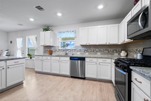 kitchen with white cabinets, appliances with stainless steel finishes, sink, and light wood-type flooring