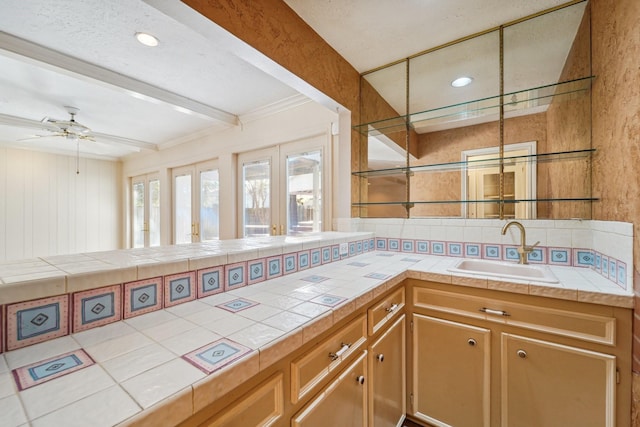 kitchen with ceiling fan, tile counters, french doors, and sink