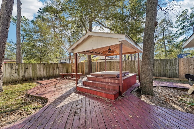 deck featuring ceiling fan, a gazebo, a fenced backyard, and a covered hot tub