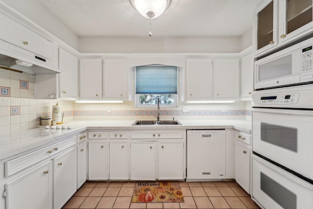 kitchen with white appliances, decorative backsplash, light countertops, white cabinetry, and a sink