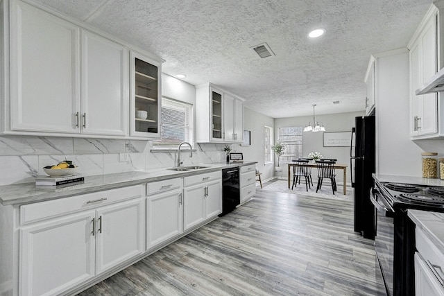 kitchen with sink, hanging light fixtures, white cabinets, and black appliances