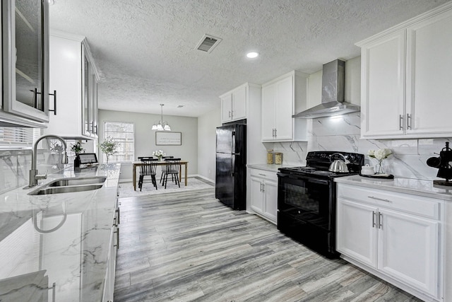 kitchen featuring black appliances, sink, white cabinetry, wall chimney exhaust hood, and light stone counters