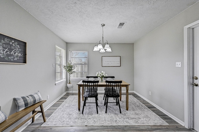 dining space featuring a notable chandelier, a textured ceiling, and hardwood / wood-style flooring