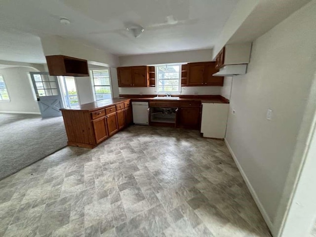 kitchen with white dishwasher, light colored carpet, kitchen peninsula, and sink