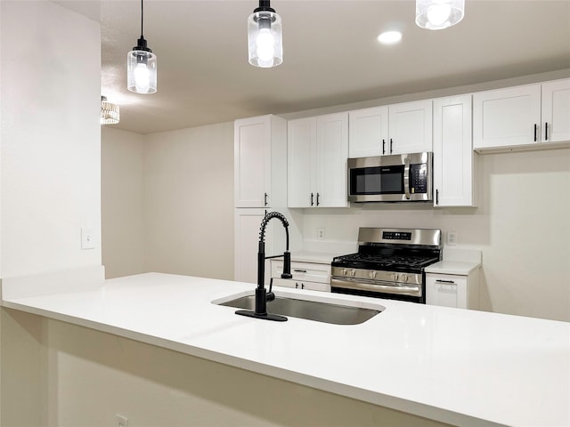 kitchen featuring appliances with stainless steel finishes, sink, white cabinetry, and pendant lighting