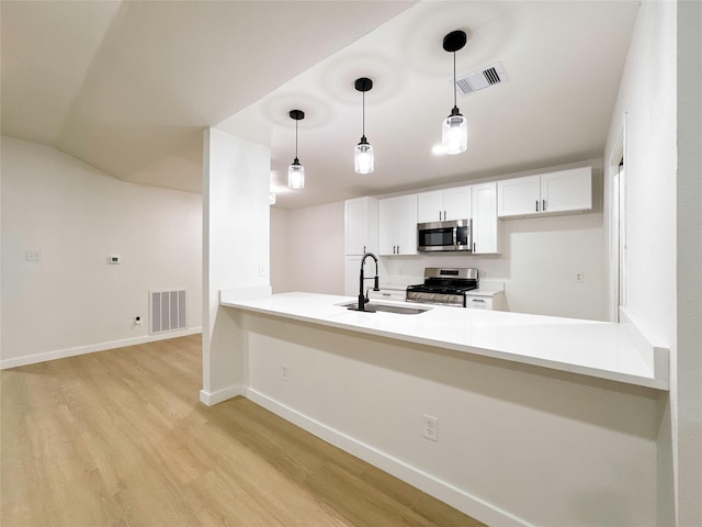 kitchen featuring white cabinetry, kitchen peninsula, stainless steel appliances, pendant lighting, and sink