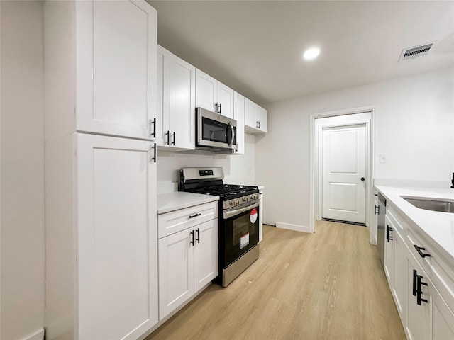 kitchen featuring sink, white cabinetry, stainless steel appliances, and light wood-type flooring