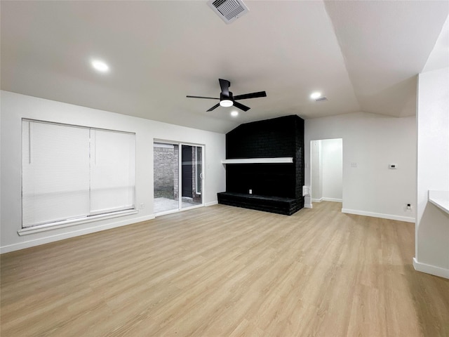 unfurnished living room featuring ceiling fan, lofted ceiling, light hardwood / wood-style flooring, and a brick fireplace