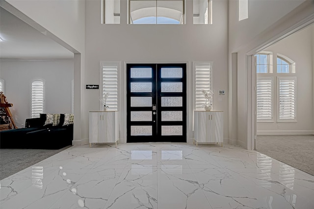 entrance foyer featuring a high ceiling, light colored carpet, and french doors