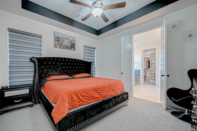 bedroom with ceiling fan, carpet flooring, a raised ceiling, and ensuite bath