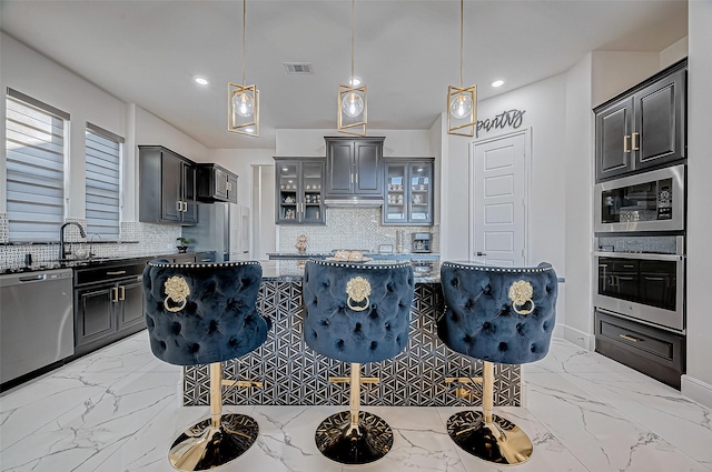 kitchen featuring stainless steel appliances, pendant lighting, a kitchen bar, and a center island