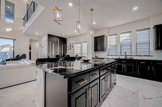 kitchen with decorative backsplash, decorative light fixtures, a chandelier, dark stone counters, and a kitchen island