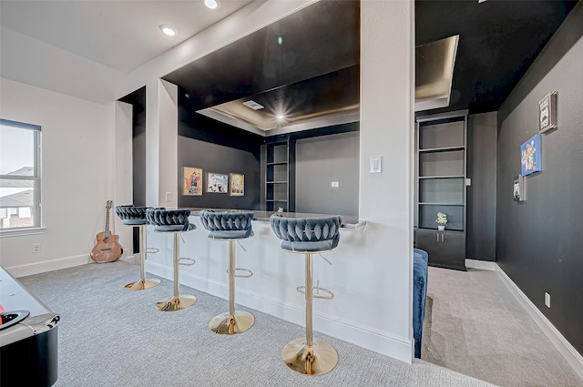 kitchen featuring a kitchen breakfast bar, light colored carpet, and built in features