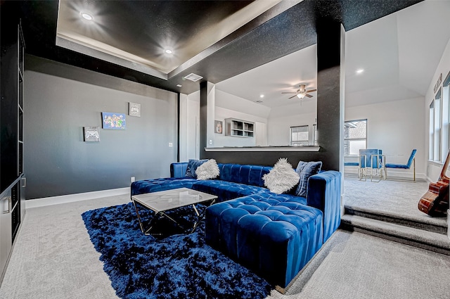 carpeted living room with ceiling fan and a raised ceiling