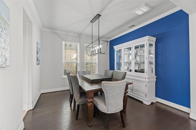 dining area with dark wood-type flooring, crown molding, and a notable chandelier