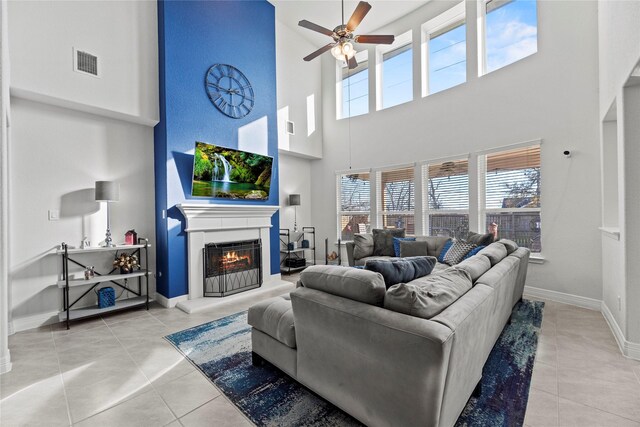 living room with ceiling fan, light tile patterned floors, and a towering ceiling