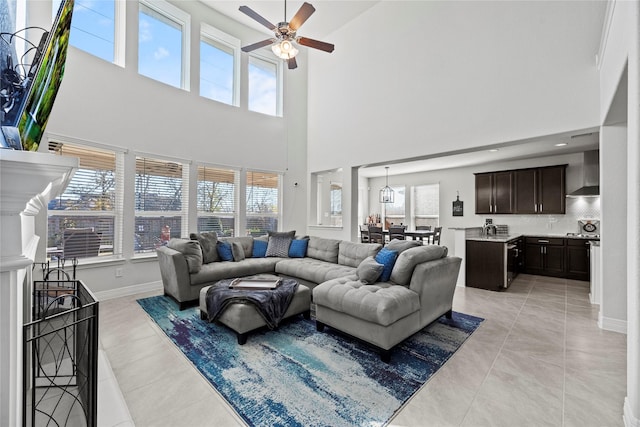 living room featuring ceiling fan, light tile patterned floors, and a towering ceiling