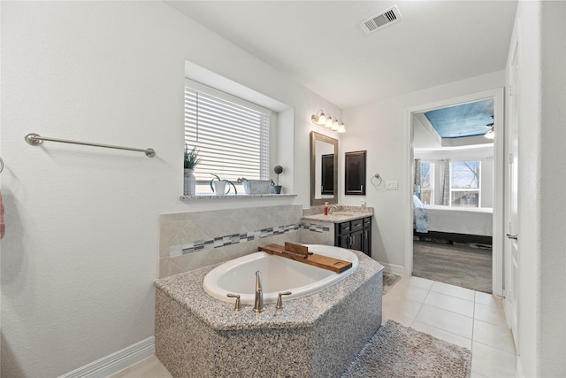 bathroom featuring tiled bath, a healthy amount of sunlight, tile patterned flooring, and vanity