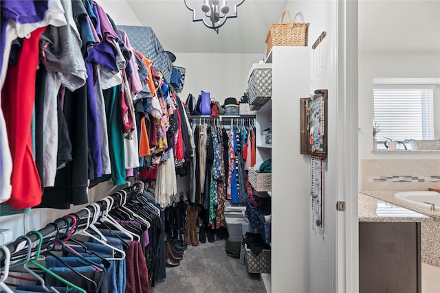 spacious closet featuring a chandelier and carpet flooring