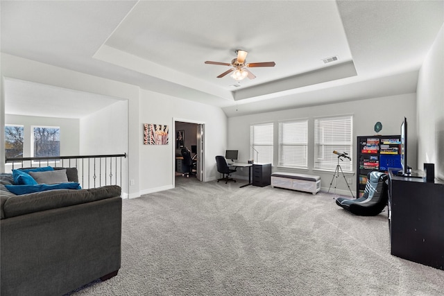 living room with ceiling fan, carpet floors, and a raised ceiling