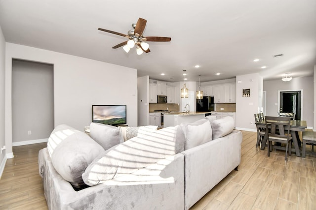 living room with ceiling fan, light hardwood / wood-style flooring, and sink