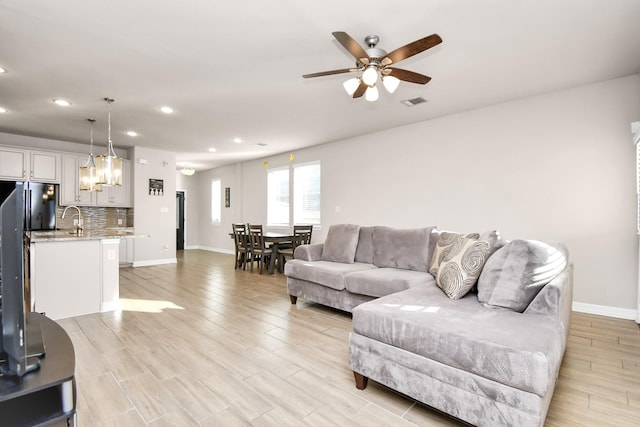 living room with light wood-type flooring, ceiling fan, and sink