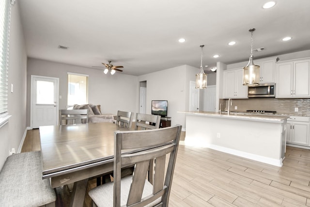 dining room featuring ceiling fan, light wood-type flooring, and sink