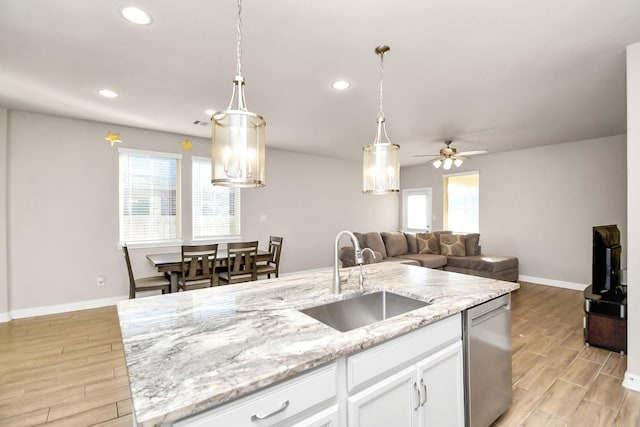 kitchen featuring ceiling fan, dishwasher, a center island with sink, sink, and white cabinets