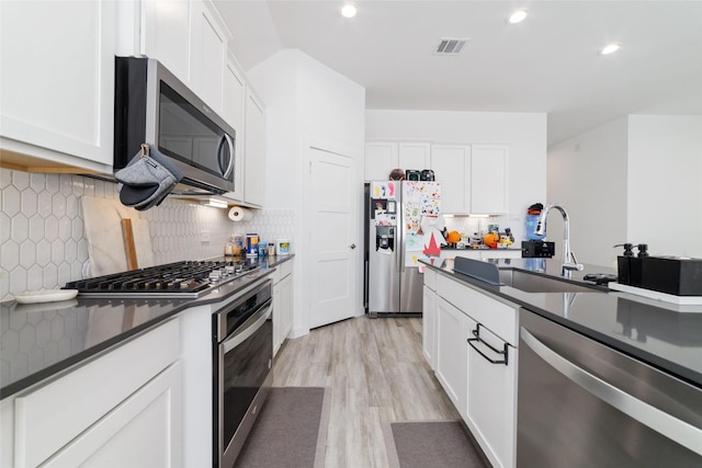 kitchen with tasteful backsplash, white cabinets, sink, and stainless steel appliances