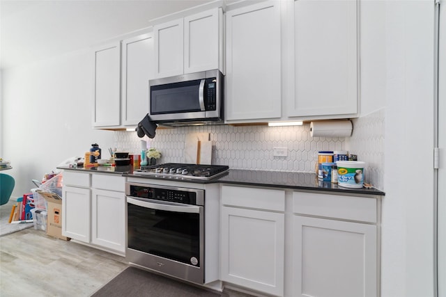 kitchen featuring light wood-type flooring, appliances with stainless steel finishes, decorative backsplash, and white cabinets