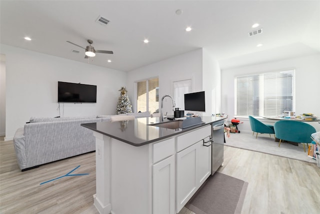 kitchen with ceiling fan, stainless steel dishwasher, light wood-type flooring, an island with sink, and white cabinets