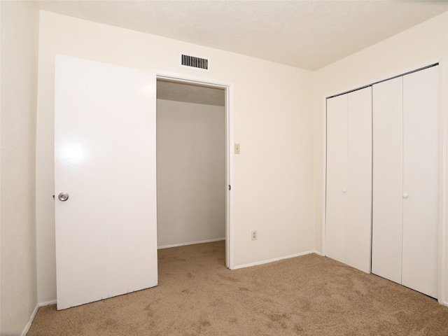 unfurnished bedroom with light colored carpet and a closet