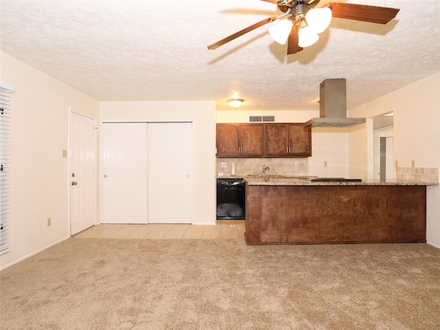 kitchen with island range hood, black appliances, light stone counters, kitchen peninsula, and light carpet