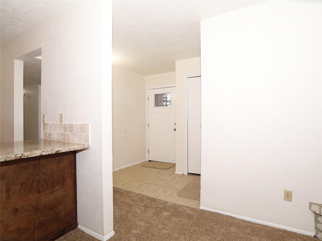 hallway with light colored carpet and a textured ceiling