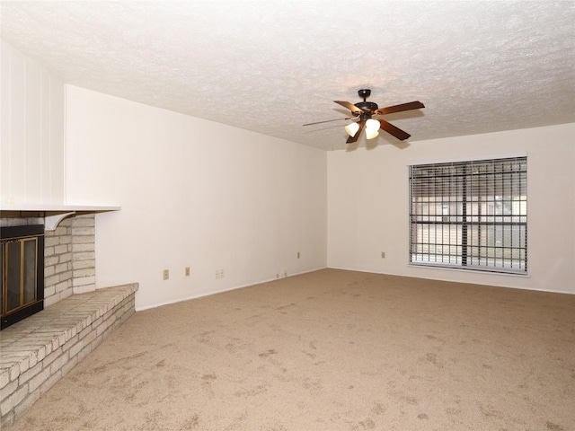 unfurnished living room with ceiling fan, carpet flooring, a brick fireplace, and a textured ceiling