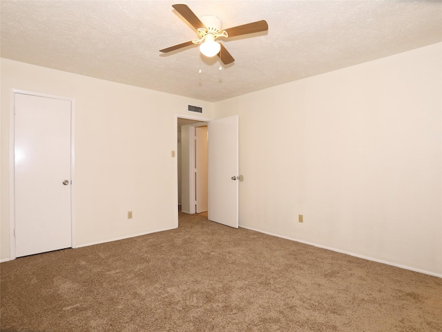 carpeted spare room featuring ceiling fan and a textured ceiling