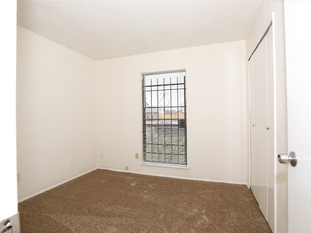 carpeted empty room featuring a textured ceiling