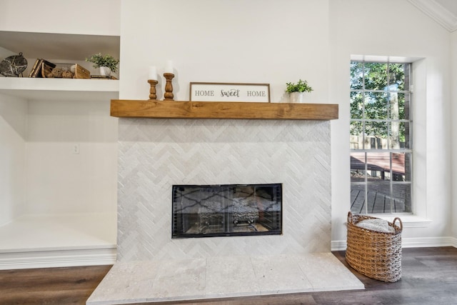 details with hardwood / wood-style flooring, crown molding, and a tiled fireplace